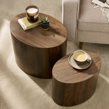 Overhead view of two dark wood oval nest tables with candle and cup, beside beige sofa on carpet