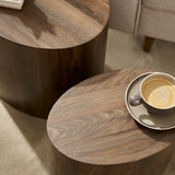 Close-up of dark wood oval table tops with visible grain and coffee cup on smaller table beside sofa