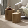 Two light oak oval nest tables beside white fabric sofa, one with coffee cup, in soft carpeted room