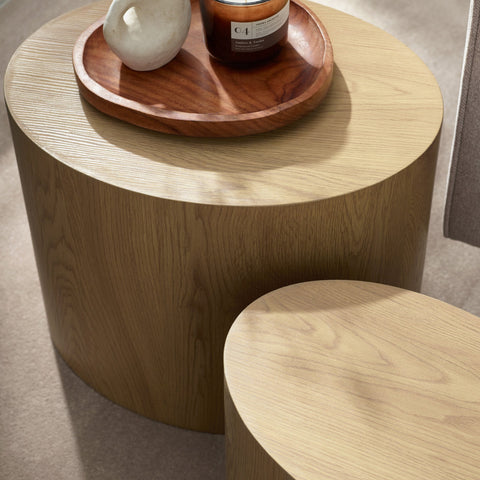 Close-up of light oak table tops showing wood grain, with a wooden tray holding a candle and small vase.