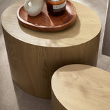 Close-up of light oak table tops showing wood grain, with a wooden tray holding a candle and small vase.