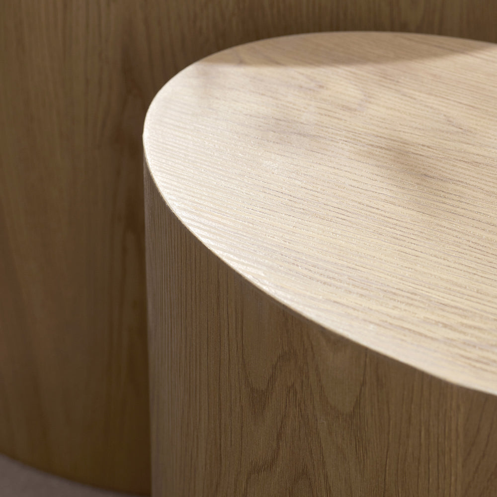 Close-up detail of rounded edge and textured wood grain on light oak oval table.