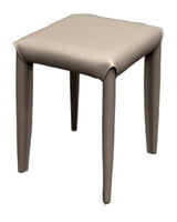 A modern square stool with a light taupe faux leather upholstered seat and slim tapered legs, shown on a plain white background.