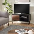 Small TV unit in black wood with one walnut door and open shelves, living room setting with gray sofa