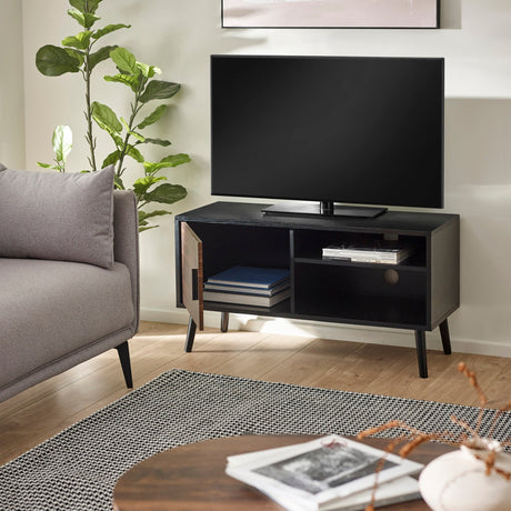 Small black wood TV unit with walnut door open showing shelves and books, next to gray sofa in living room