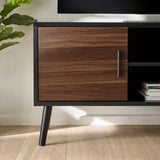 Close-up of black TV unit frame with walnut wood cabinet door and metal handle, standing on light wood floor