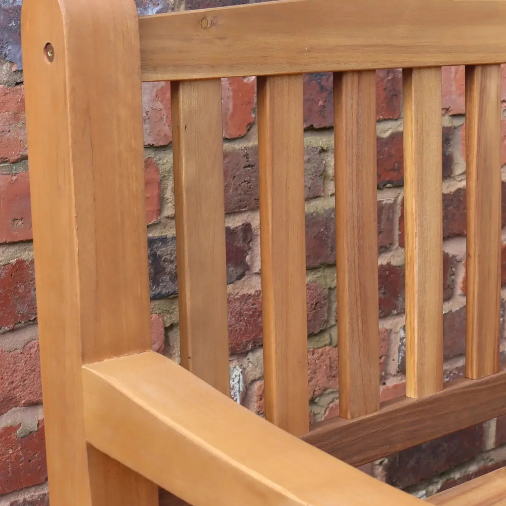 Teak wooden garden bench backrest and armrest detail against brick wall