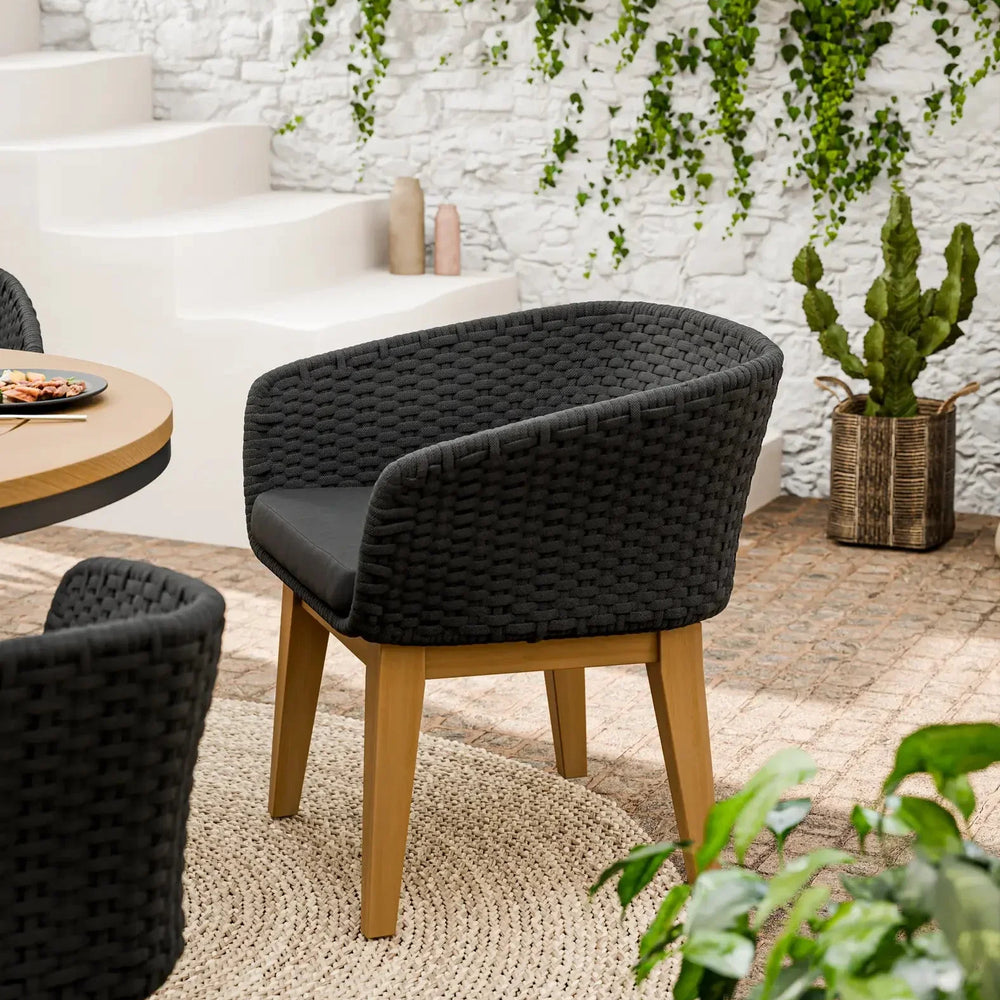 Black woven dining chair with wooden legs on beige rug in modern indoor setting