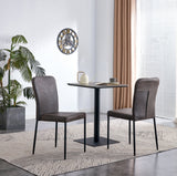 Grey upholstered dining chairs with black pedestal dining table in a bright modern dining room.