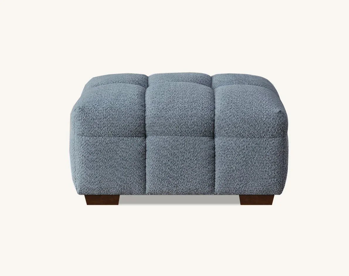 Grey fabric upholstered ottoman stool with square tufted design and dark wooden legs