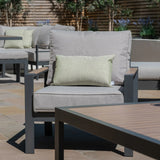 Grey outdoor armchair with wooden arms and light green cushion on patio with matching sofa