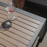 Slatted outdoor coffee table with metal frame, glass of water and strawberry on coaster