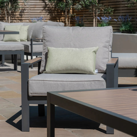 Grey outdoor lounge chair with green cushion and metal frame on patio near matching table