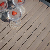 Slatted outdoor dining table in light wood finish with drinks served in glasses on coasters