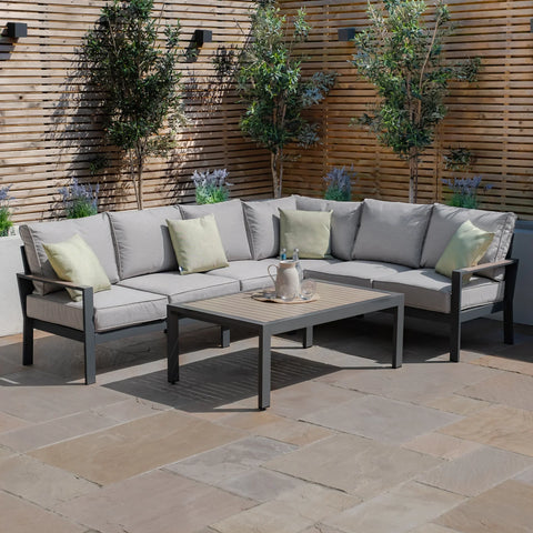 Grey outdoor corner sofa set with cushions and rectangular coffee table on patio