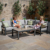 Grey outdoor corner sofa set with cushions and coffee table on a stone patio