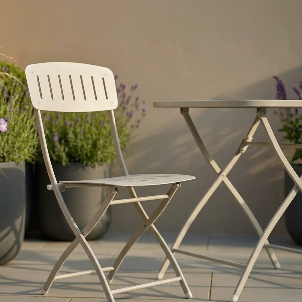 Cream metal folding patio chair and table set on tiled outdoor terrace