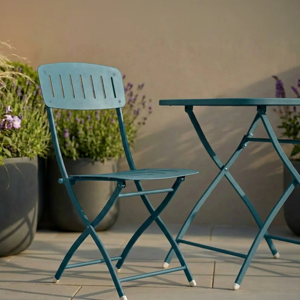 Teal metal garden chair and foldable table on patio with potted plants in background