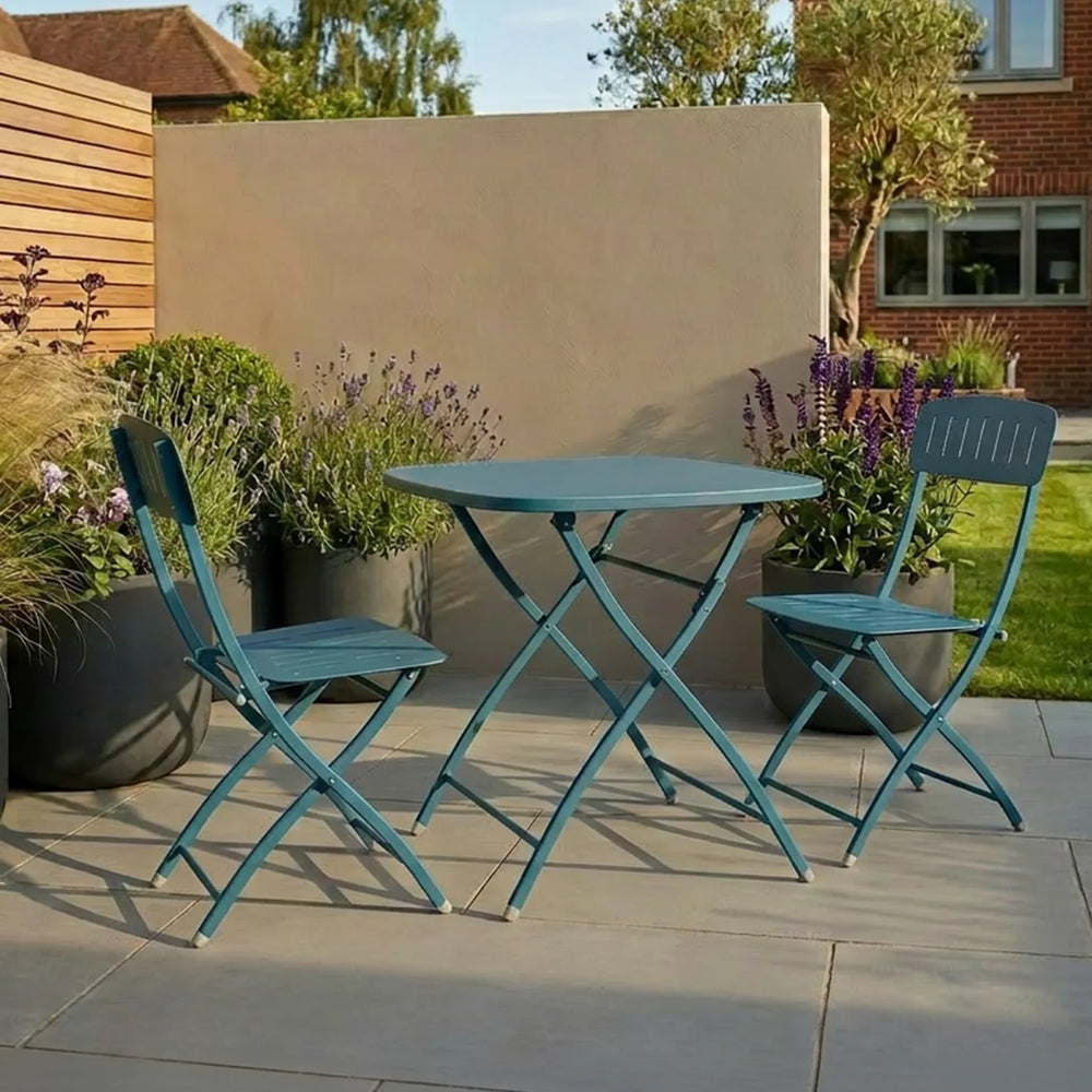 Blue metal bistro set with round table and two chairs on patio surrounded by potted plants