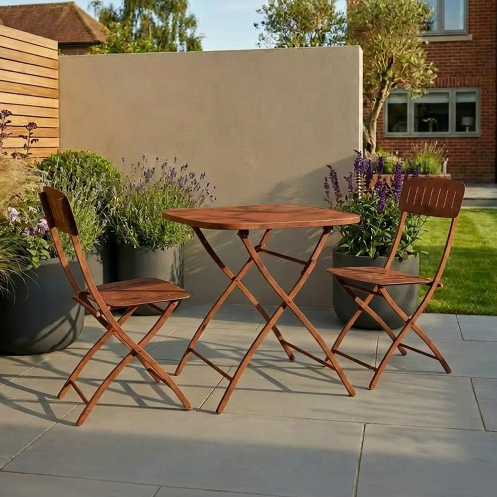 Wooden bistro garden table with two matching folding chairs on a patio with plants