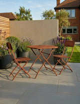 Wooden bistro garden table with two matching folding chairs on a patio with plants