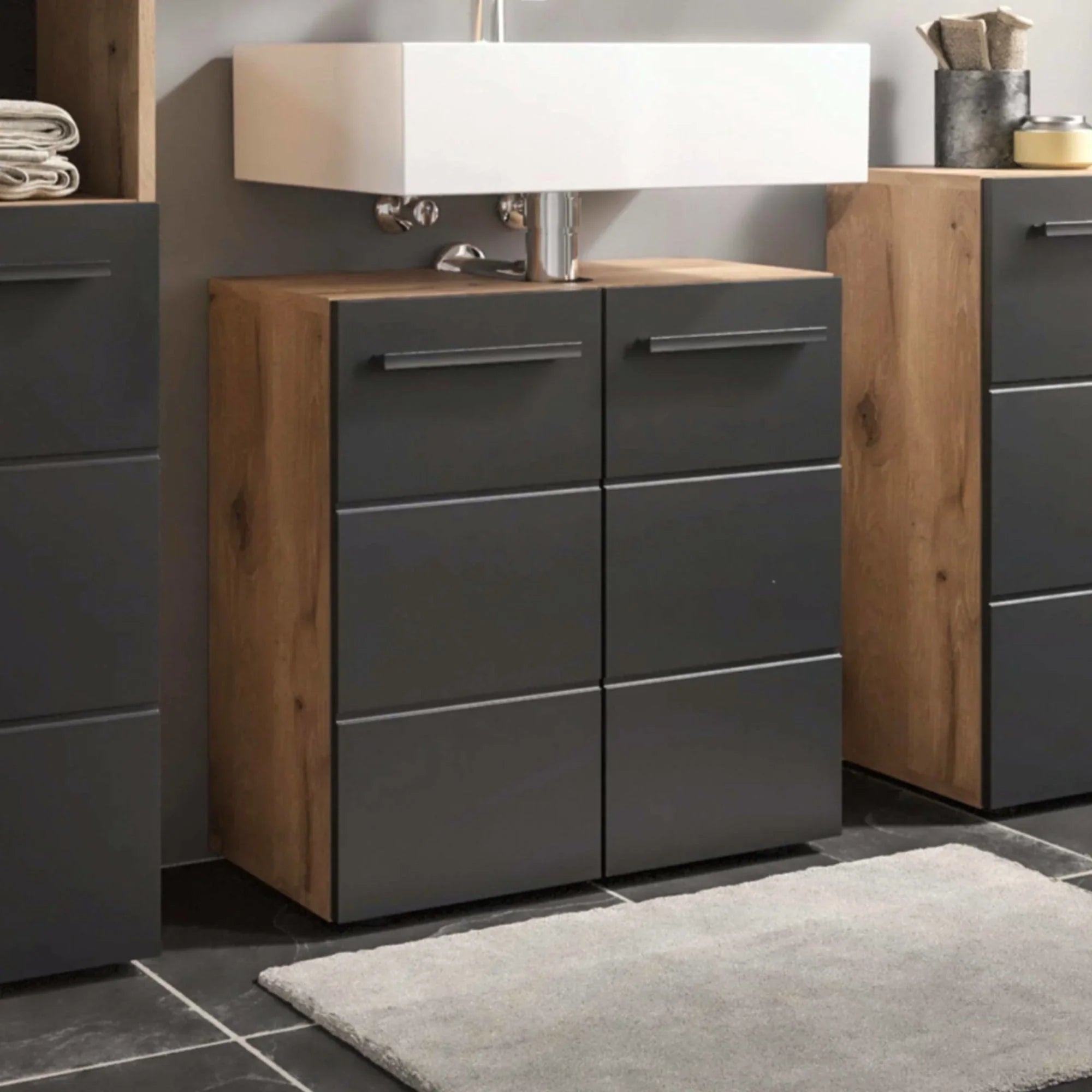 Modern bathroom vanity unit with black drawers and wood sides beneath white basin