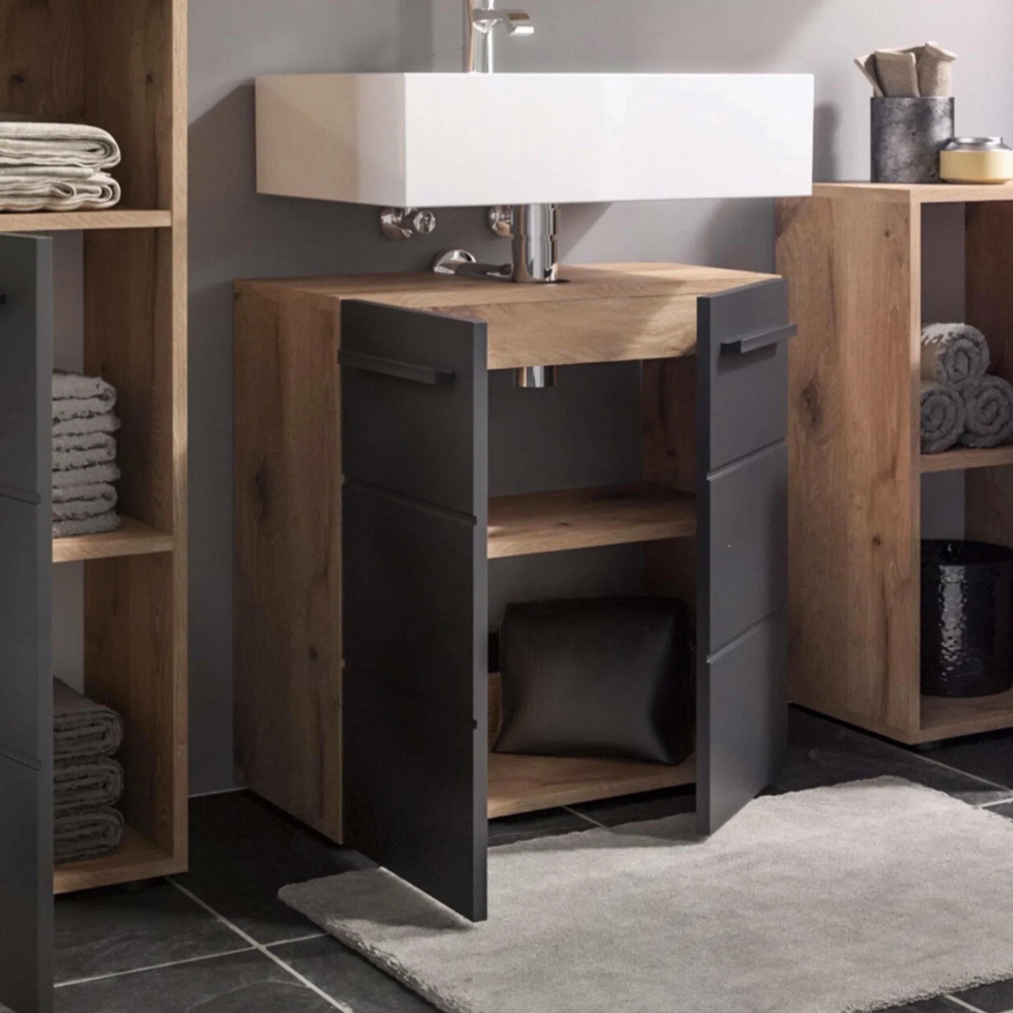 Oak bathroom vanity unit with black doors and open shelving below white basin sink