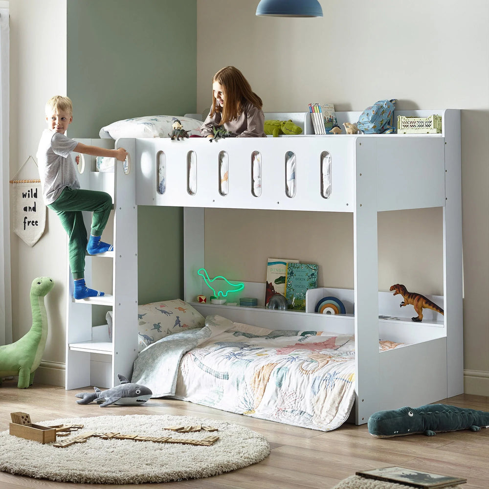 white wooden bunk bed with ladder in kids bedroom, dinosaur decor, books and toys visible