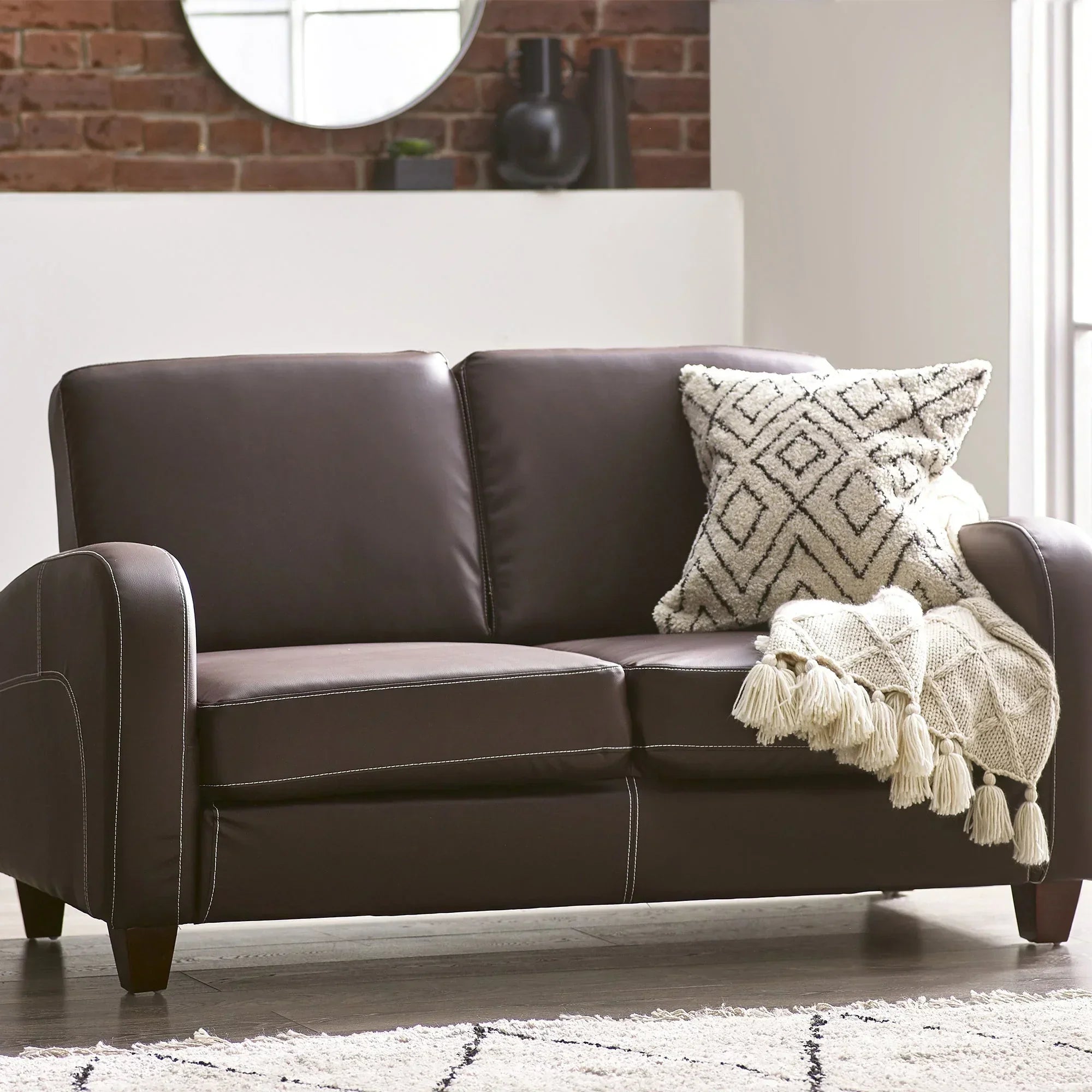 Brown 2 seater sofa with cream textured throw and patterned cushion in modern living room