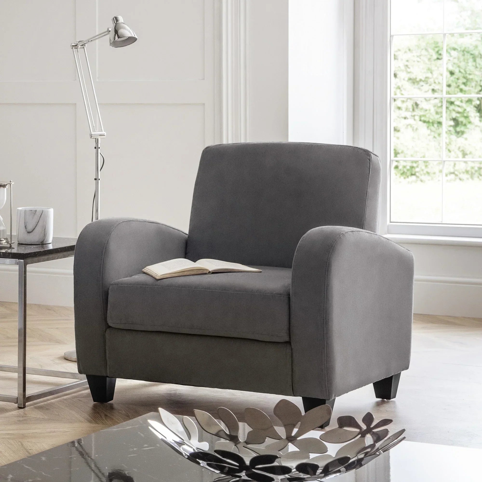 Dusk grey velvet sofa chair in modern living room beside side table and window