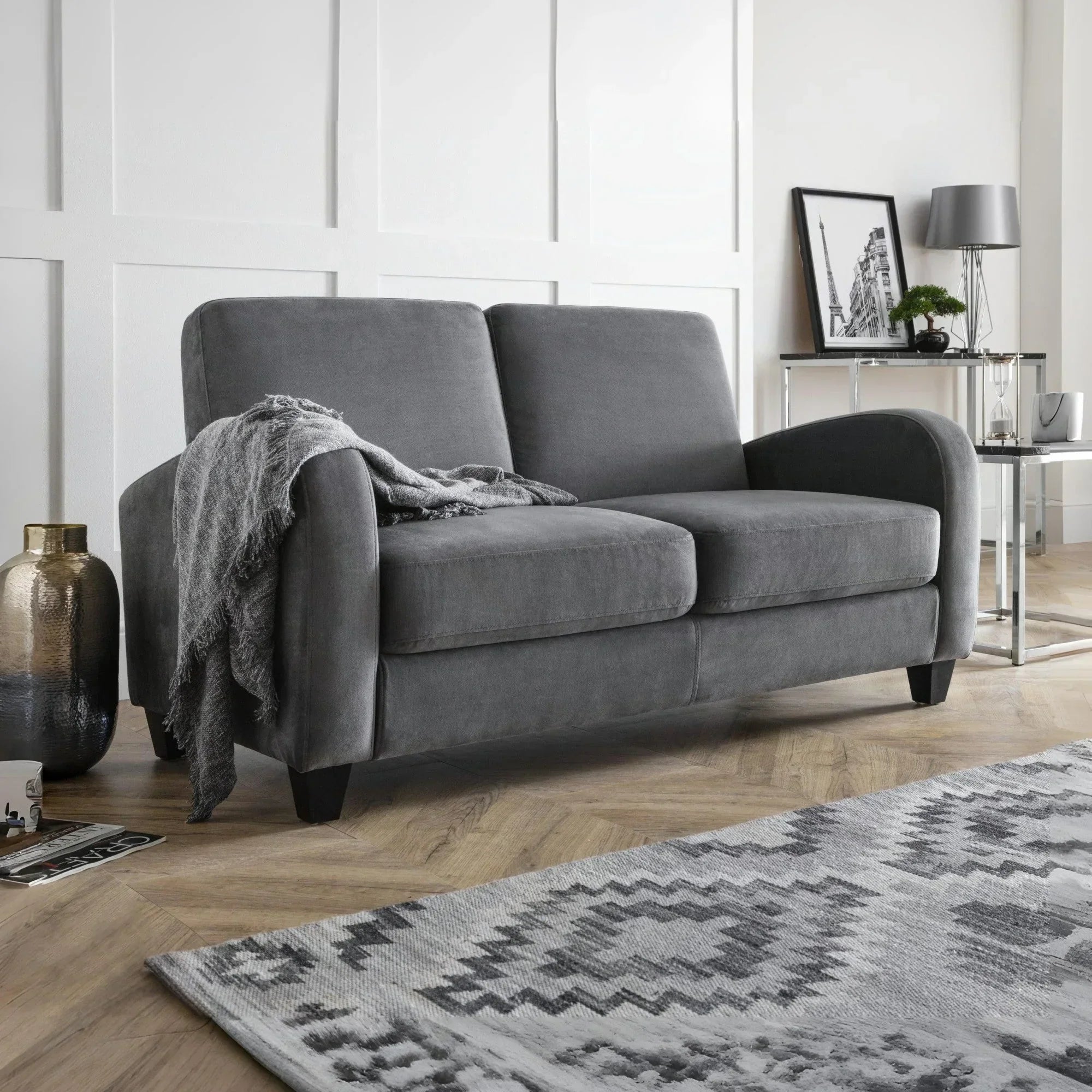Grey fabric sofa with two seat cushions, throw blanket, wooden legs, in a modern living room