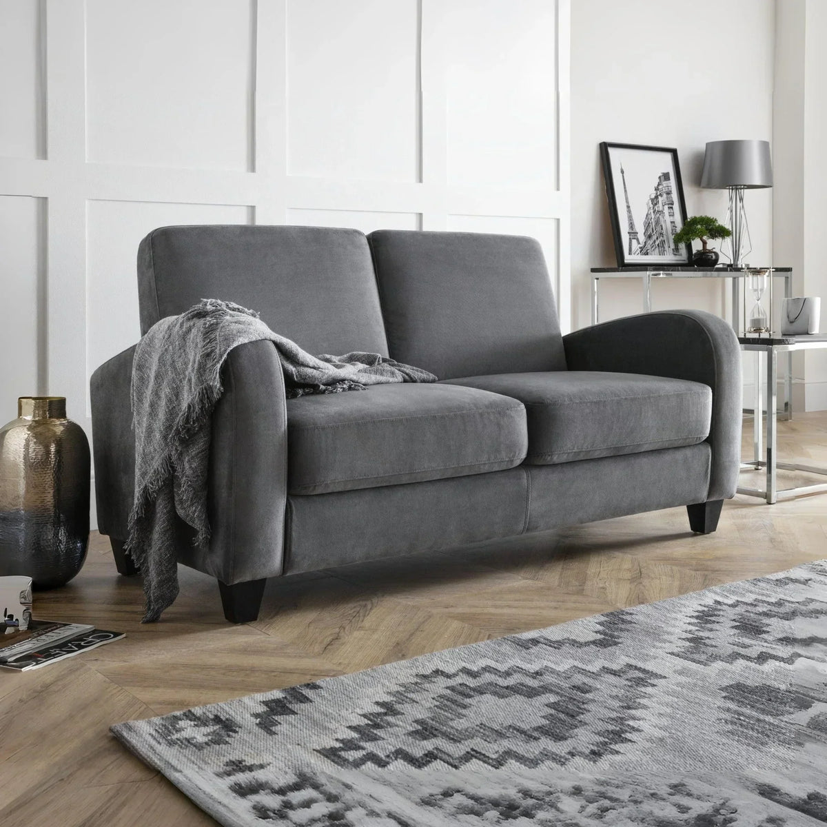 Grey fabric sofa with two seat cushions, throw blanket, wooden legs, in a modern living room