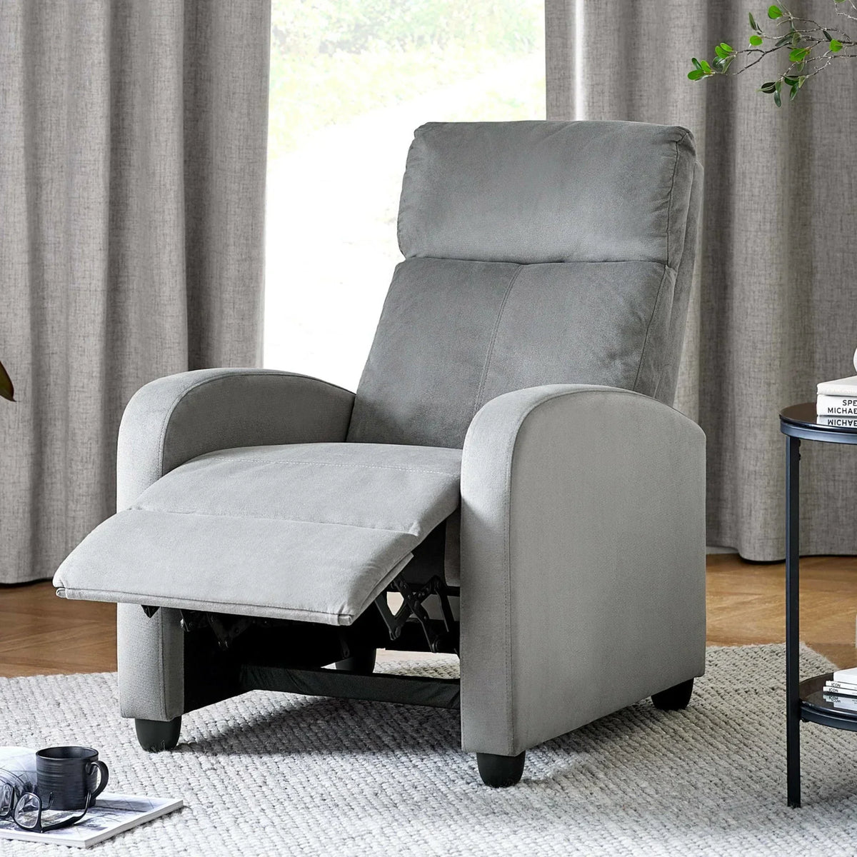 Grey fabric recliner chair with footrest extended in living room with neutral decor