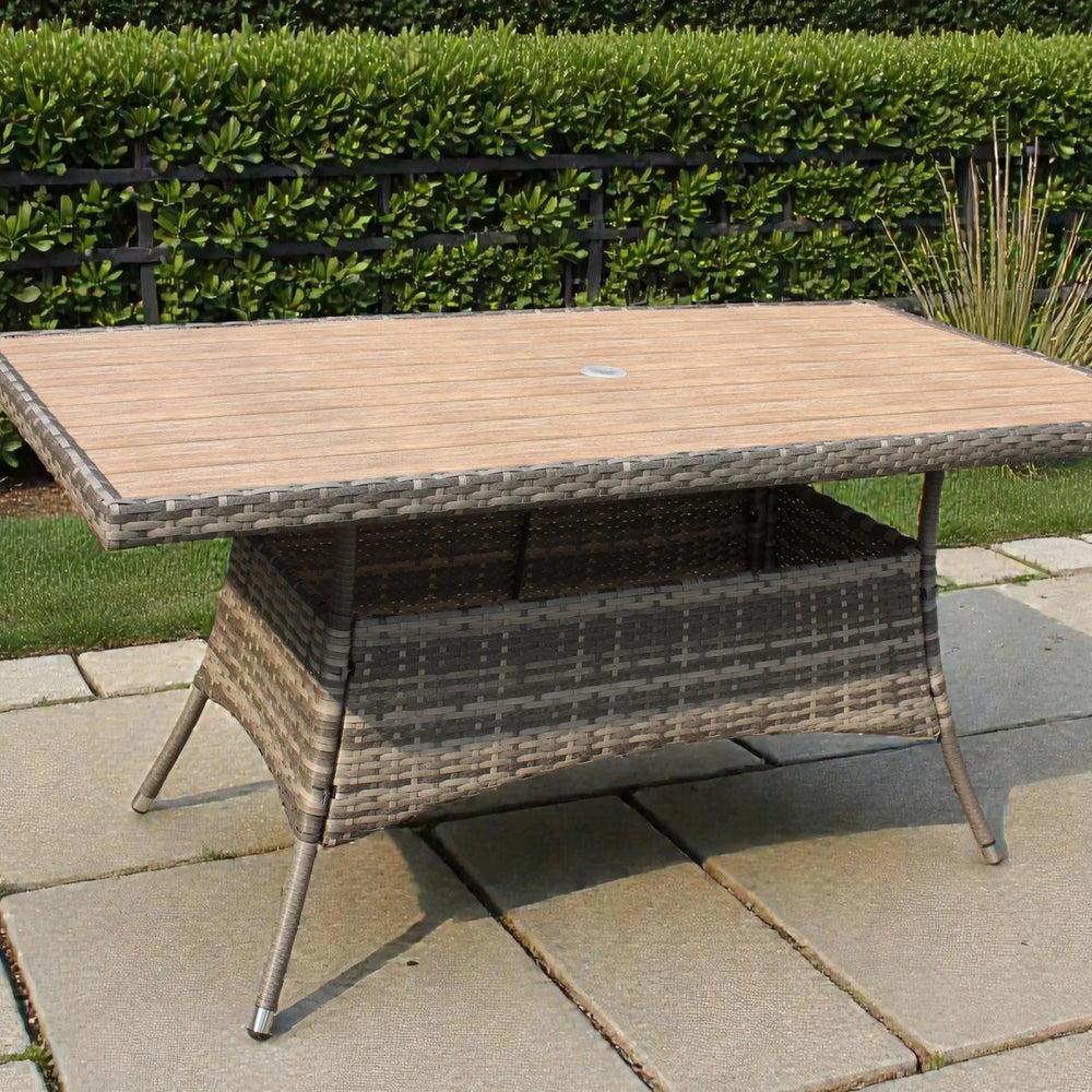 Rectangular rattan garden table with wood-effect top on stone patio