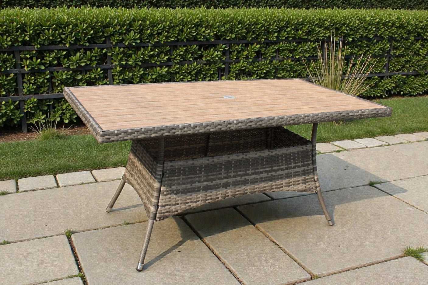 Rectangular rattan garden table with wood-effect top on stone patio