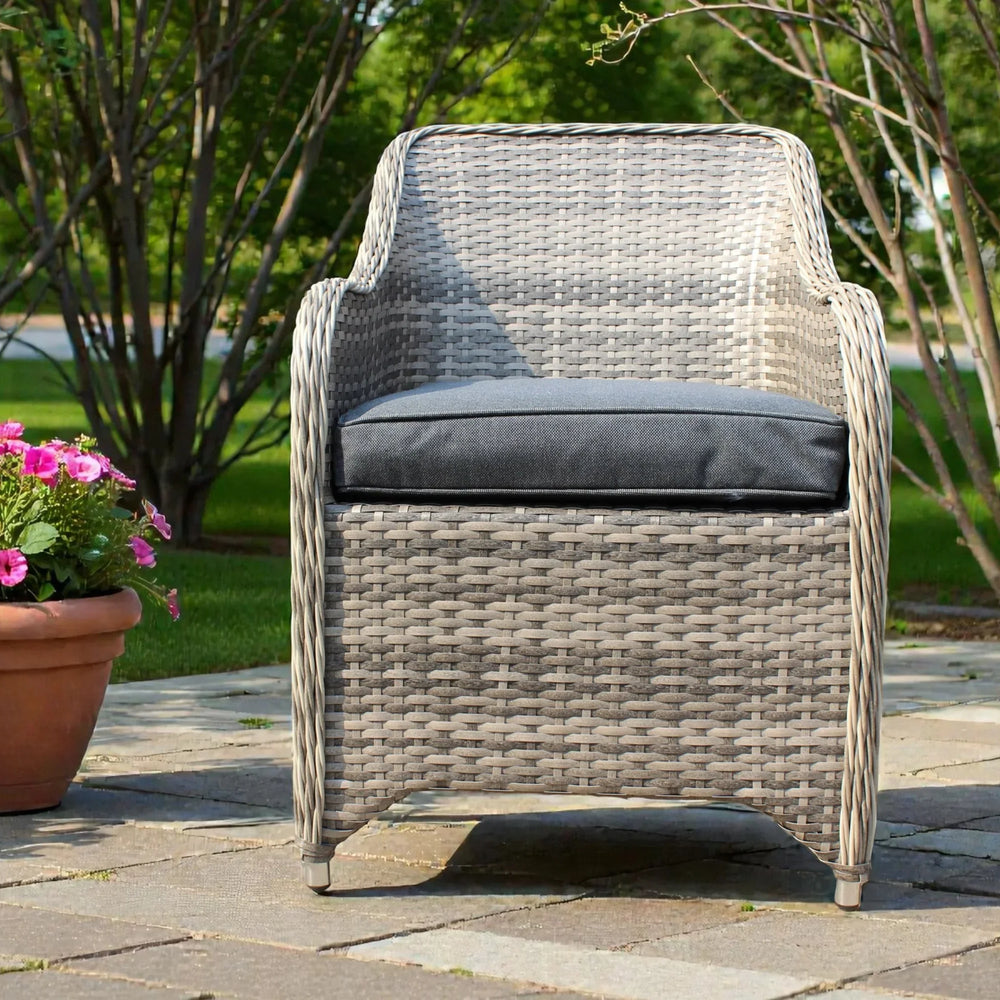 Grey rattan garden chair with dark cushion on patio, pink flowers in terracotta pot beside