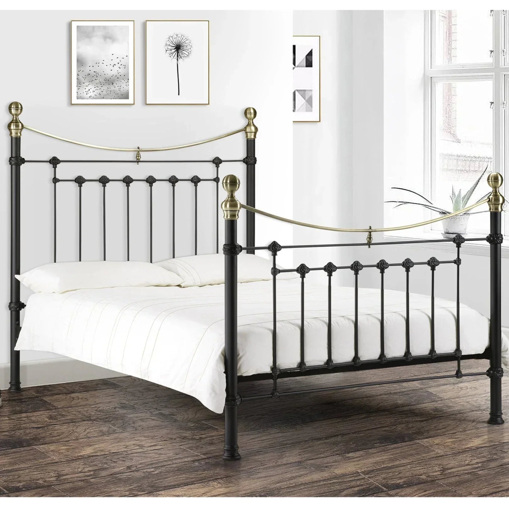 Black metal bed frame with brass accents, white bedding, in modern bedroom with wood floor