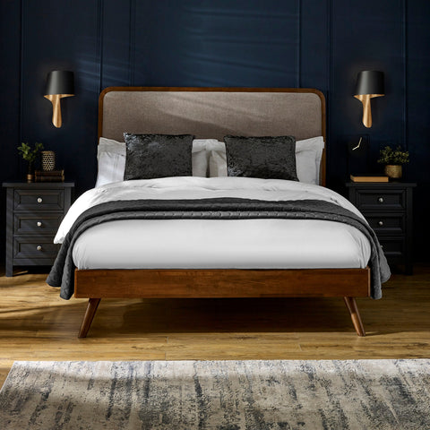Walden bed with dark wood frame, beige upholstered headboard, white bedding, black pillows in navy room