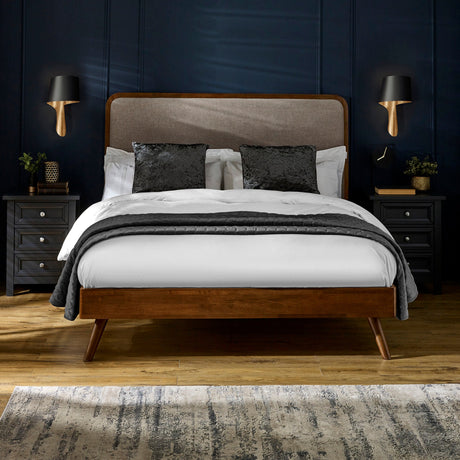 Walden bed with dark wood frame, beige upholstered headboard, white bedding, black pillows in navy room