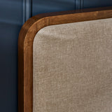 Close-up of curved dark wood frame edge and beige upholstered headboard of Walden bed