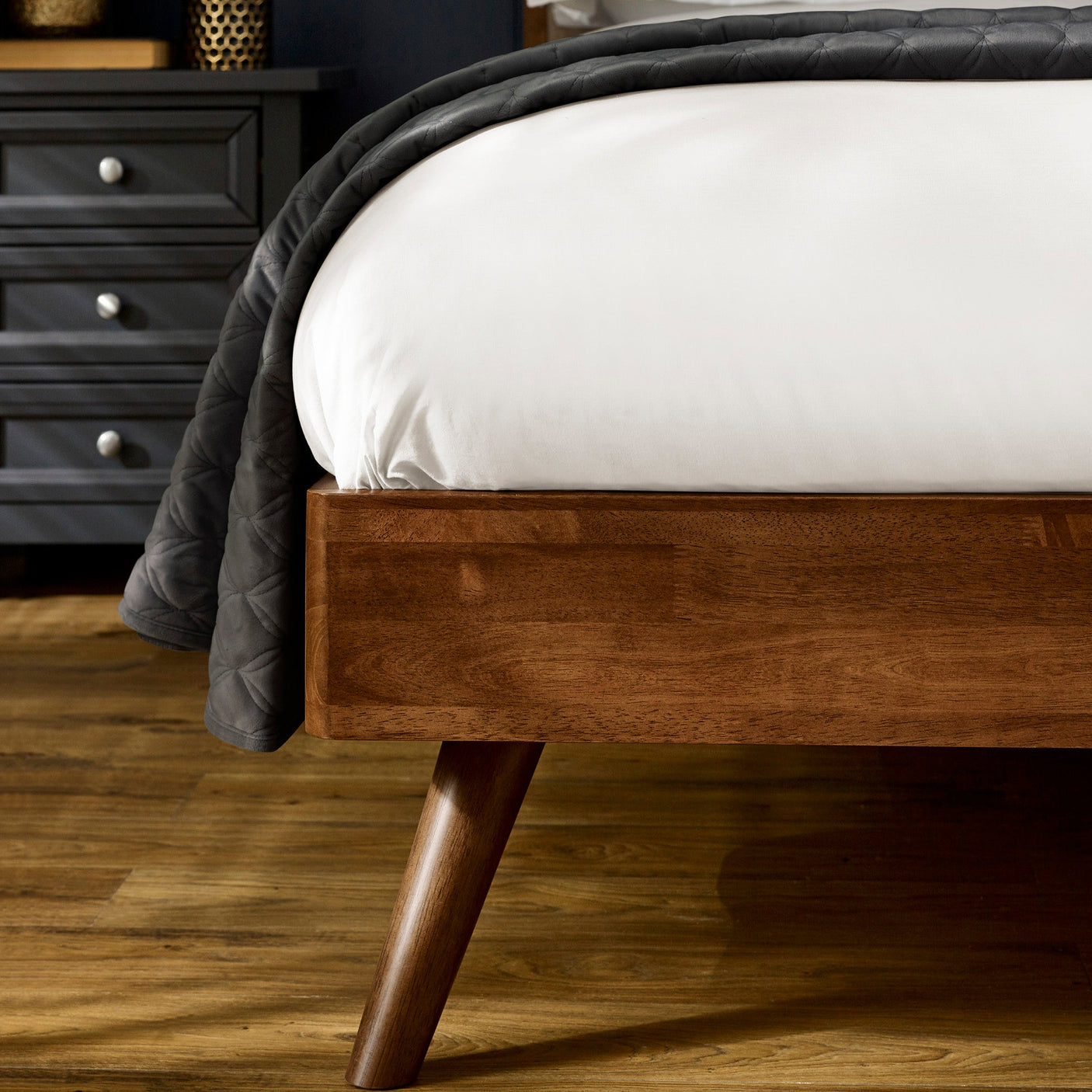 Walden bed dark wood tapered leg supporting frame with white bedding and dark quilt