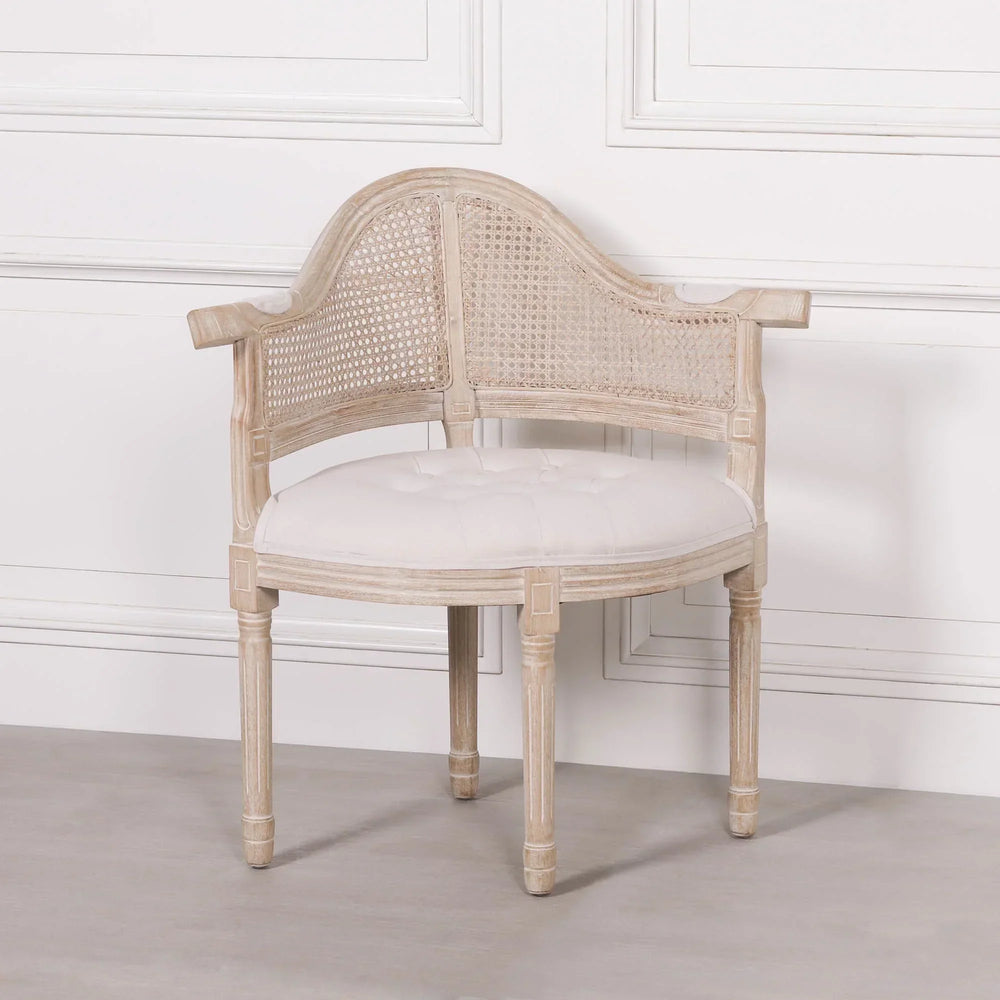 Wooden corner chair with cane backrest and white cushioned seat against panelled wall