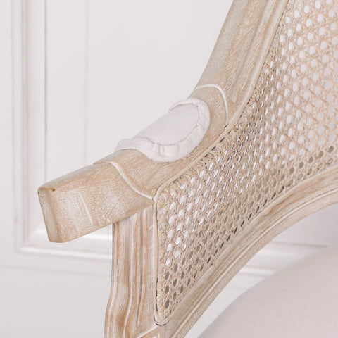 Close view of rattan armchair with light oak wood finish and cushioned armrest