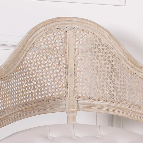 Light oak cane back dining chair with tufted cream seat close-up