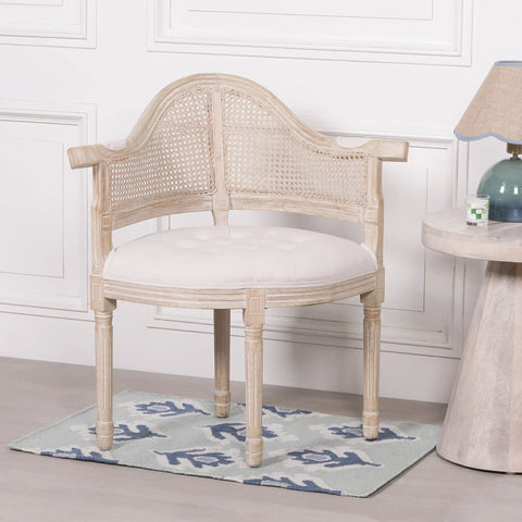 Wooden accent chair with cane backrest and white upholstered seat beside round side table