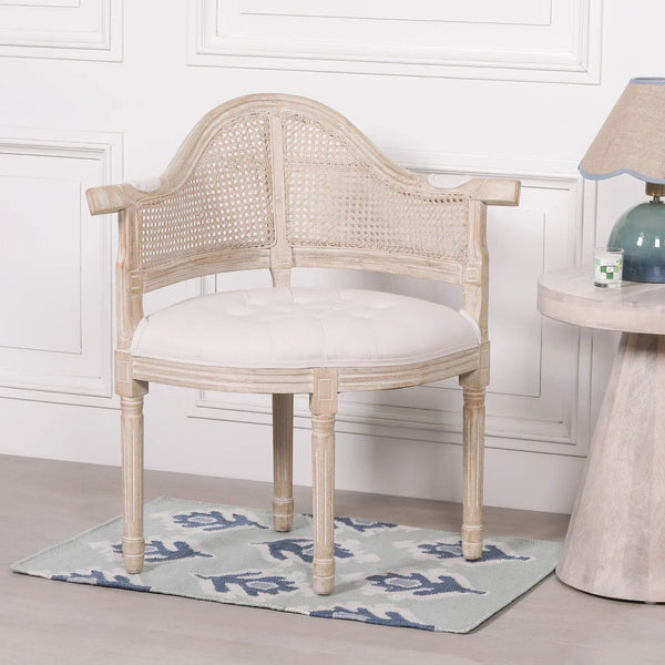 Wooden accent chair with cane backrest and white upholstered seat beside round side table