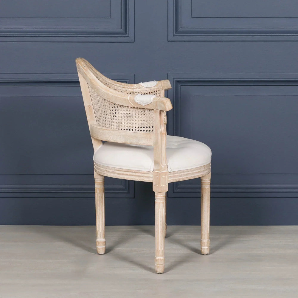 Light wood dining chair with curved cane back and cream upholstered seat, side view