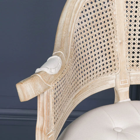 Close-up of rattan armchair with light wood frame and tufted cream cushion