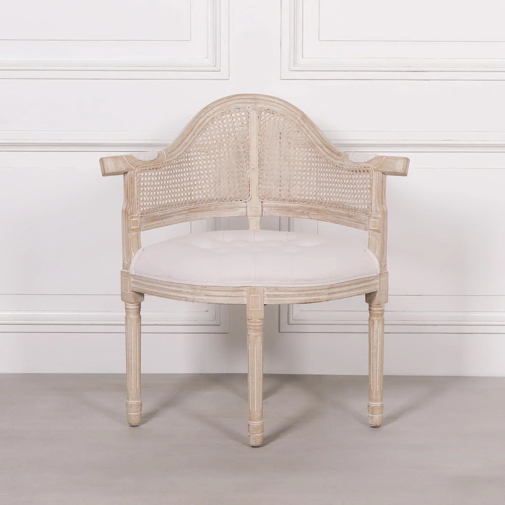 Light wood accent chair with cane backrest and white upholstered seat against a white wall