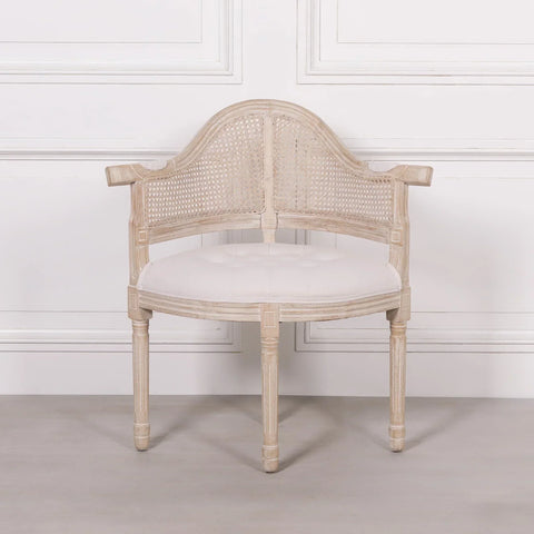 Light wood accent chair with cane backrest and white upholstered seat against a white wall
